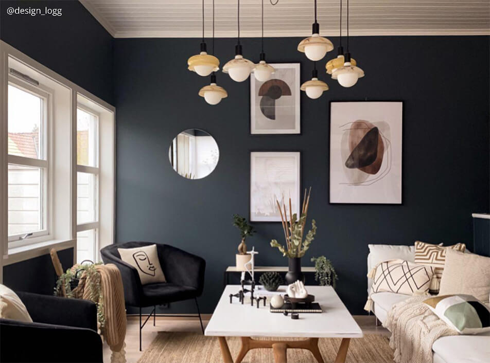 Σαλόνι με σκοτεινούς τοίχους, μαύρες βελούδινες πολυθρόνες, στρογγυλός καθρέφτης, γραφικές αφίσες