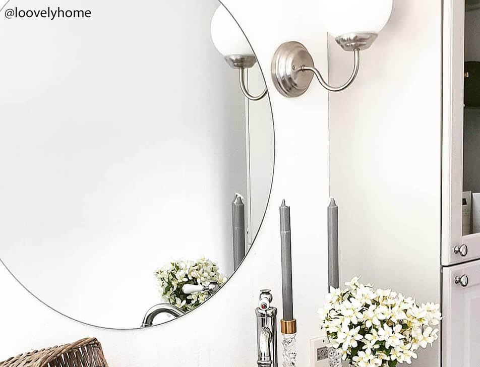 Στρογγυλός καθρέφτης, λουλούδια και κερί στο μπάνιο